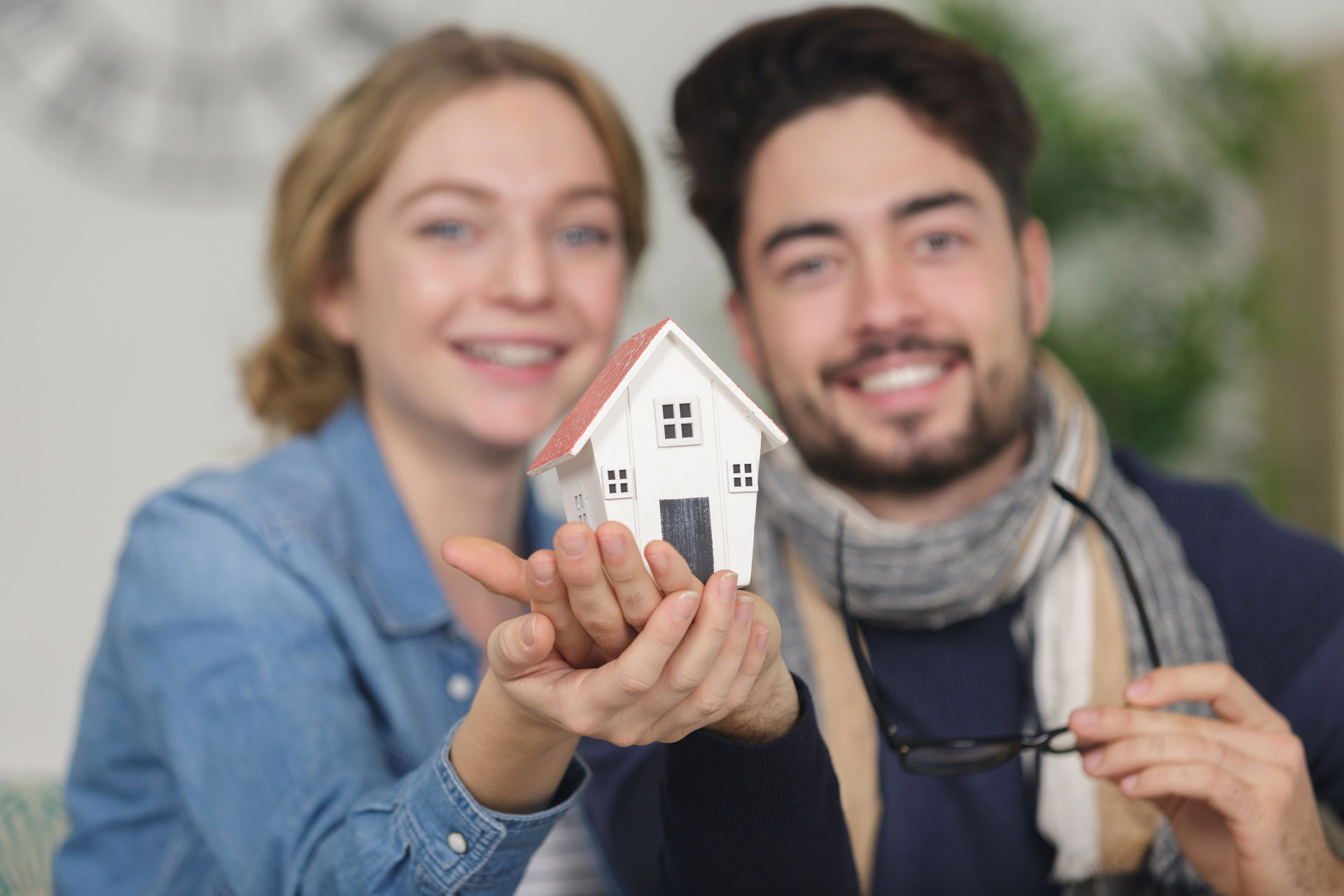 Glückliches Paar hält Modellhaus in Händen